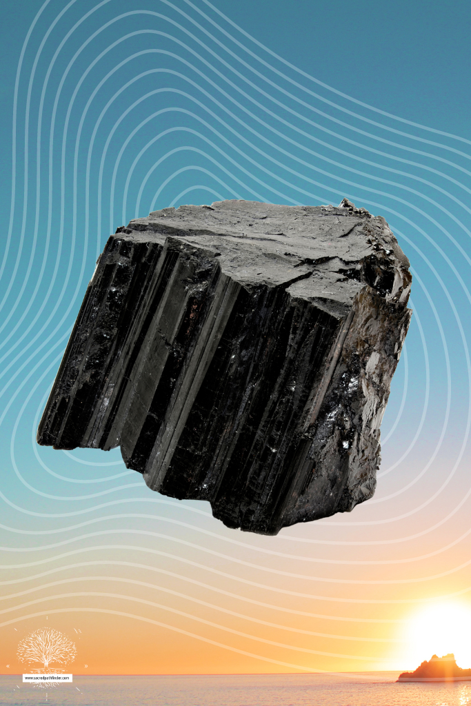 Photo of black tourmaline in front of a sunset background.