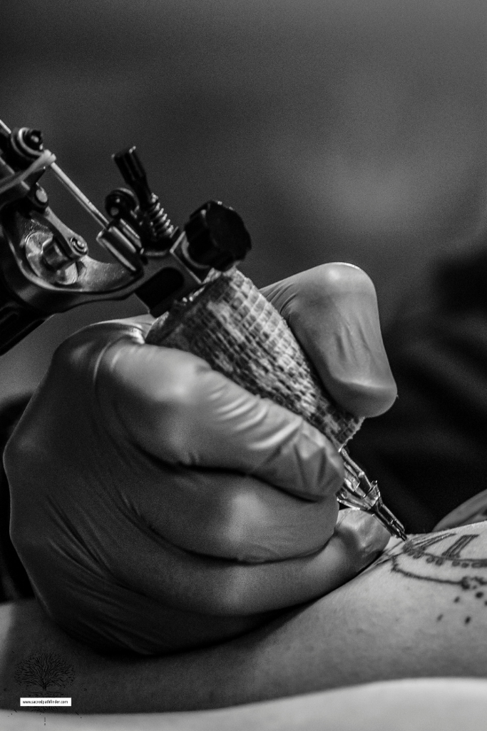 Closeup photo of a hand tattooing a person. 