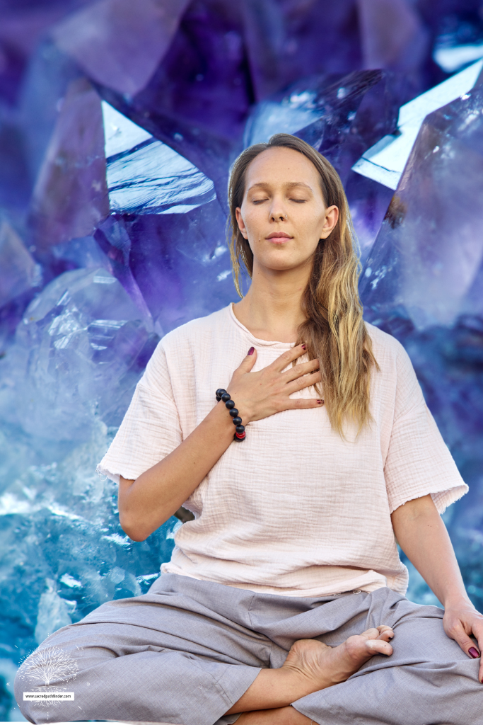 Photo of a woman meditating in front of a crystal background.