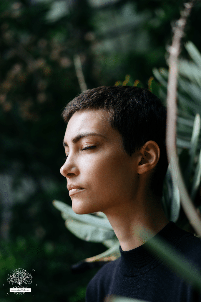 Photo of a person with short hair, with their eyes closed, and looking peaceful, in front of a jungle background.