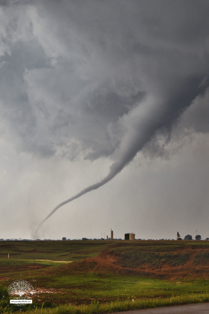 Photo of a tornado from a distance, touching down to a flat ground. 