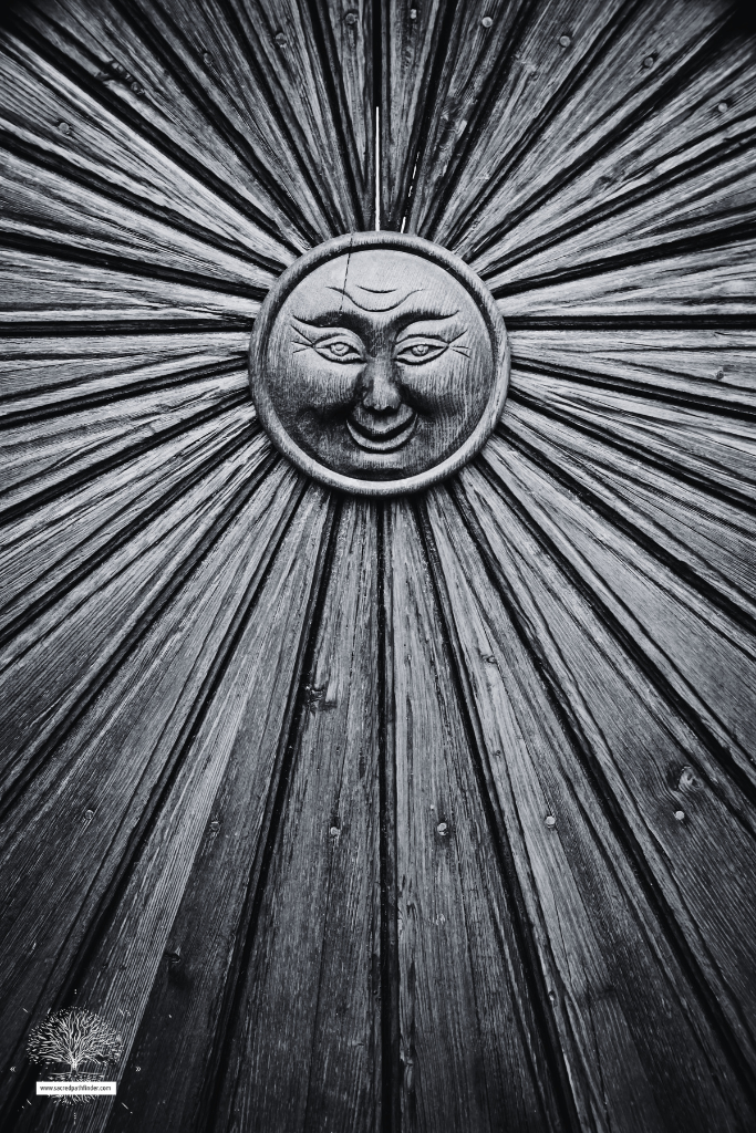 Black and white photo of a wooden sun symbol.