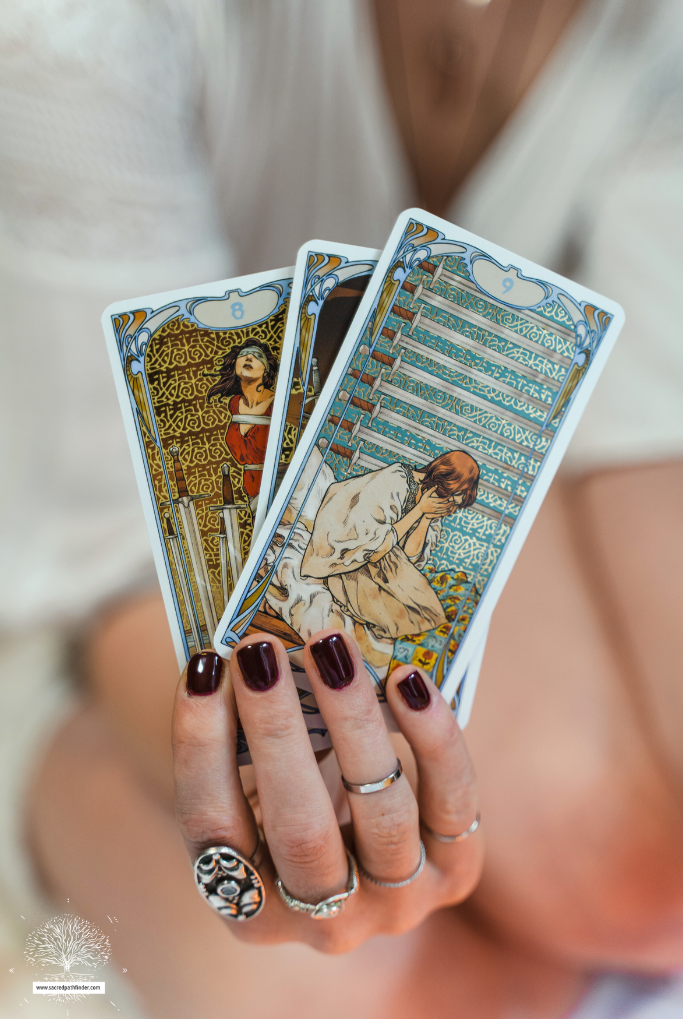 Photo of a hand holding up tarot cards. 